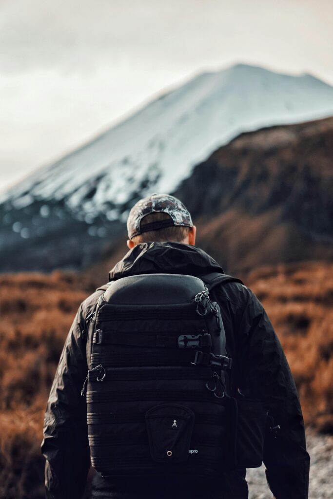 Back view of a hiker exploring mountainous terrain in daylight.